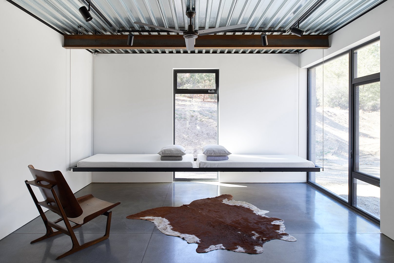 Guest bedroom interior of Tom Kundig Sawmill House in Tehachapi, California, featuring minimalist furnishings, two suspended single beds and curated accessories, styled by Stephen Pappas Interiors for Princeton Architectural Press book "Tom Kundig Wo